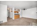 Spacious living room flows into an open kitchen with neutral carpet and a ceiling fan at 225 E 8Th Ave # C-19, Longmont, CO 80504