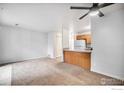 Open-concept living room with neutral carpet, ceiling fan, and adjacent kitchen at 225 E 8Th Ave # C-19, Longmont, CO 80504