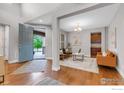 Bright foyer with hardwood floors, an open floor plan, and blue front door at 2264 Front Range Rd, Erie, CO 80516