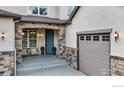 Inviting covered porch with stylish seating, stone accents, and a blue front door at 2264 Front Range Rd, Erie, CO 80516