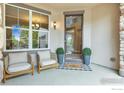 Inviting covered porch with stylish seating and view into entry way at 2264 Front Range Rd, Erie, CO 80516