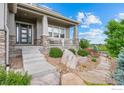 Inviting covered front porch with stone accents and manicured landscaping at 3075 Blue Mountain Dr, Broomfield, CO 80023