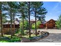Beautiful log home with stone accents, a large driveway, and mature trees create a picturesque and private setting at 409 Wild Horse Cir, Boulder, CO 80304