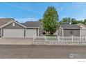 Spacious two-car garage with a white picket fence, and a storage shed at 5111 Mt St Vrain Ave, Frederick, CO 80504