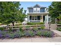 Lovely two-story home with a charming front porch, white railings, and a beautifully landscaped yard with vibrant purple flowers at 518 Hoyt Ln, Lafayette, CO 80026