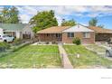 Charming brick home with a well-maintained lawn, fence and pathway leading to the entrance at 547 S Eliot St, Denver, CO 80219