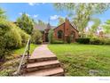 Inviting home featuring a stone pathway, stairs with a handrail, lush lawn, and mature landscaping at 1226 Dexter St, Denver, CO 80220