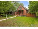 Charming brick home with a well-maintained lawn and inviting front porch surrounded by mature trees at 205 E Colorado Ave, Berthoud, CO 80513