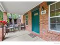 Inviting front porch of brick home, complete with seating and decorative plants and green door at 205 E Colorado Ave, Berthoud, CO 80513