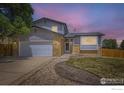 Charming two-story home with a well-maintained lawn and a two-car garage at twilight at 2447 E 100Th Way, Thornton, CO 80229