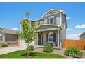 Charming two-story home featuring a covered front porch, manicured lawn, and a lovely tree at 2509 Alto St, Fort Lupton, CO 80621