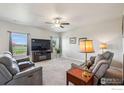 Inviting living room featuring plush seating, neutral walls, plush carpet, and a ceiling fan at 2509 Alto St, Fort Lupton, CO 80621