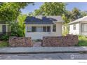 Charming single-story home featuring a red brick retaining wall and cozy, enclosed porch at 29 Marshall Pl, Longmont, CO 80504