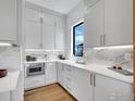 Modern kitchen boasts white cabinets, drawers, marble backsplash, stainless steel microwave, and sleek countertops at 354 Troon Ct, Louisville, CO 80027