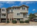 View of a townhome with brick and gray siding and a partially covered garage, surrounded by greenery at 4947 Noble Park Pl, Boulder, CO 80301