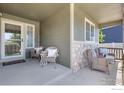 Inviting covered front porch with stone accents and comfortable wicker seating at 5869 Vinca Ave, Longmont, CO 80504