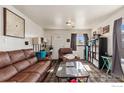 Cozy living room featuring a comfortable brown leather sofa, recliner, and a glass coffee table at 6743 King St, Denver, CO 80221