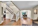 Inviting foyer showcasing hardwood floors, a staircase with carpet, and a view into the dining room at 11740 Ivy St, Thornton, CO 80233