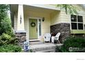 Inviting front porch area with stylish chairs, stone accents, and a beautifully decorated front door at 1847 White Feather Dr, Longmont, CO 80504