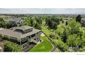 An elevated view of a home with a stone facade, a wooden staircase leading to a second-story deck, and lush green surroundings at 24725 E Dry Creek Pl, Aurora, CO 80016