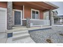 Covered front porch with stone pillars, gray door, white railing, and gravel landscaping at 2739 Crystal Springs Ln, Longmont, CO 80503