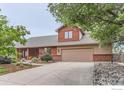 Residential home with wide driveway, two-car garage, and manicured landscaping in the front at 5420 Crestone Cir, Boulder, CO 80301