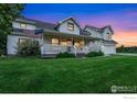 Charming front porch with a swing, American flag, and well-manicured lawn at 7215 Hygiene Rd, Longmont, CO 80503