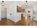 Bright foyer with hardwood floors, white wainscoting, and decorative lighting at 7215 Hygiene Rd, Longmont, CO 80503
