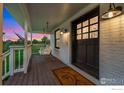 Cozy porch featuring a hanging swing, stylish lighting, and a welcoming door at 7215 Hygiene Rd, Longmont, CO 80503
