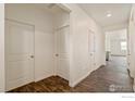 A view of the interior hallway with multiple doors and dark laminate floors at 845 Leeward St, Lochbuie, CO 80603