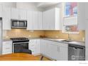 White kitchen has stainless appliances, a center island, and hardwood floors at 876 Cimarron Dr # B, Lafayette, CO 80026