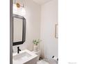 This charming powder room features a black-framed mirror, bright vanity, and a contemporary sconce at 9415 E 58Th Dr, Denver, CO 80238
