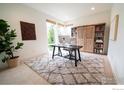 Home office with a built-in bookcase, neutral carpet, and a modern desk setup, bathed in natural light at 9415 E 58Th Dr, Denver, CO 80238