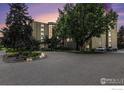 Beautiful building featuring mature trees, a circular drive, and well-manicured landscaping at 14000 E Linvale Pl # 210, Aurora, CO 80014