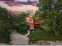 Charming two-story home with vibrant red accents and a spacious driveway, surrounded by mature trees and lush landscaping at 1484 Wicklow St, Boulder, CO 80303
