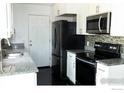 Modern kitchen featuring stainless steel appliances, granite countertops, and white cabinetry at 15532 E Pacific Pl, Aurora, CO 80013
