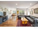 Open concept living room with hardwood floors, art and view into the dining and kitchen area at 1672 Maccullen Dr, Erie, CO 80516