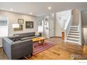 Bright and airy living room with hardwood floors, neutral walls, and staircase at 1672 Maccullen Dr, Erie, CO 80516