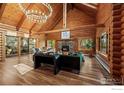 Expansive living room with vaulted ceilings, wood beams, stone fireplace and modern chandelier at 172 Tall Pine Ln, Boulder, CO 80302