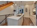 Bright kitchen featuring a large island with sink, modern cabinetry, hardwood floors, and open staircase at 2139 N Downing St, Denver, CO 80205