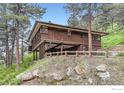 Exterior view of a split-level home with wood siding and mature trees at 27 Arrowleaf Ct, Boulder, CO 80304