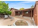 A covered back patio with brick flooring, neutral colored chairs and an empty planter at 2800 Lake Hollow Rd, Berthoud, CO 80513