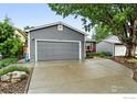 Charming home featuring a two car garage, neutral gray siding and a manicured front yard at 311 S Adams Dr, Louisville, CO 80027