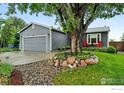 Attractive single-story home with gray siding, a two-car garage, mature landscaping, and front lawn at 311 S Adams Dr, Louisville, CO 80027