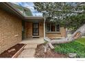 Close-up of the front porch with brick facade, metal security screen, and a mature tree providing shade at 3722 Monterey Pl, Boulder, CO 80301