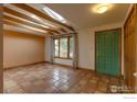 Living room featuring terracotta tile flooring, exposed wood beams, skylights, and a green paneled door at 3722 Monterey Pl, Boulder, CO 80301