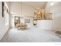 An open floor plan featuring a dining table set adjacent to the staircase, with a vaulted ceiling to the second story at 13560 Detroit St, Thornton, CO 80241