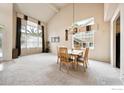 A bright and spacious dining area with large windows and a vaulted ceiling, complemented by a chandelier above the dining table at 13560 Detroit St, Thornton, CO 80241