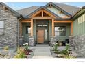 Close up front porch showcasing wooden door, stone pillars, wood beam archway, and cozy seating area at 1366 Eliza Ave, Berthoud, CO 80513