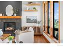 Living room featuring a modern fireplace, floating shelves, and large windows with wood trim at 1366 Eliza Ave, Berthoud, CO 80513